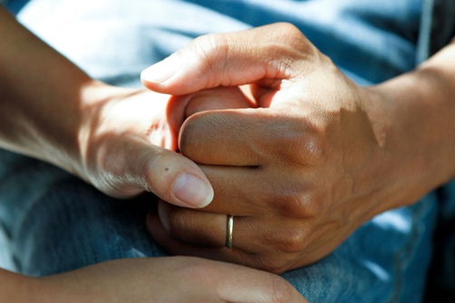 Eine Hand wird behutsam von zwei Händen gehalten