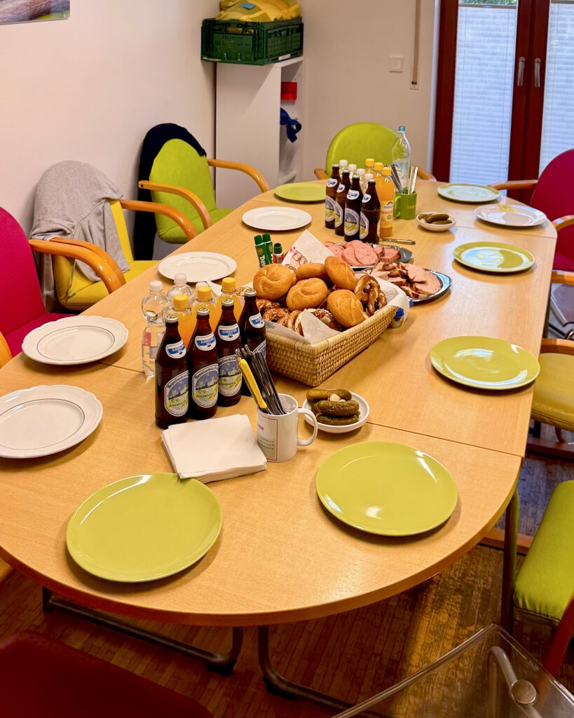Gedeckter Besprechungstisch mit Semmeln, Brezn, Leberkäs und alkoholfreien Getränken.