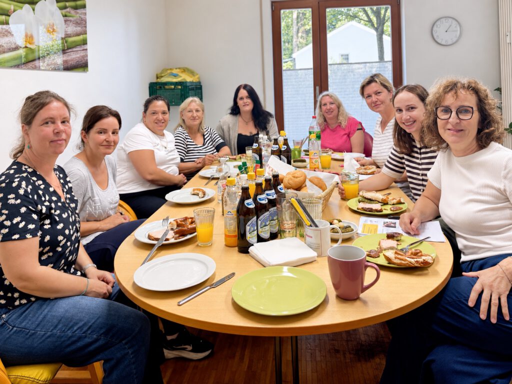 Das Pflegeteam sitzt bei der monatlichen Teambesprechung gemeinsam am gedeckten Tisch.