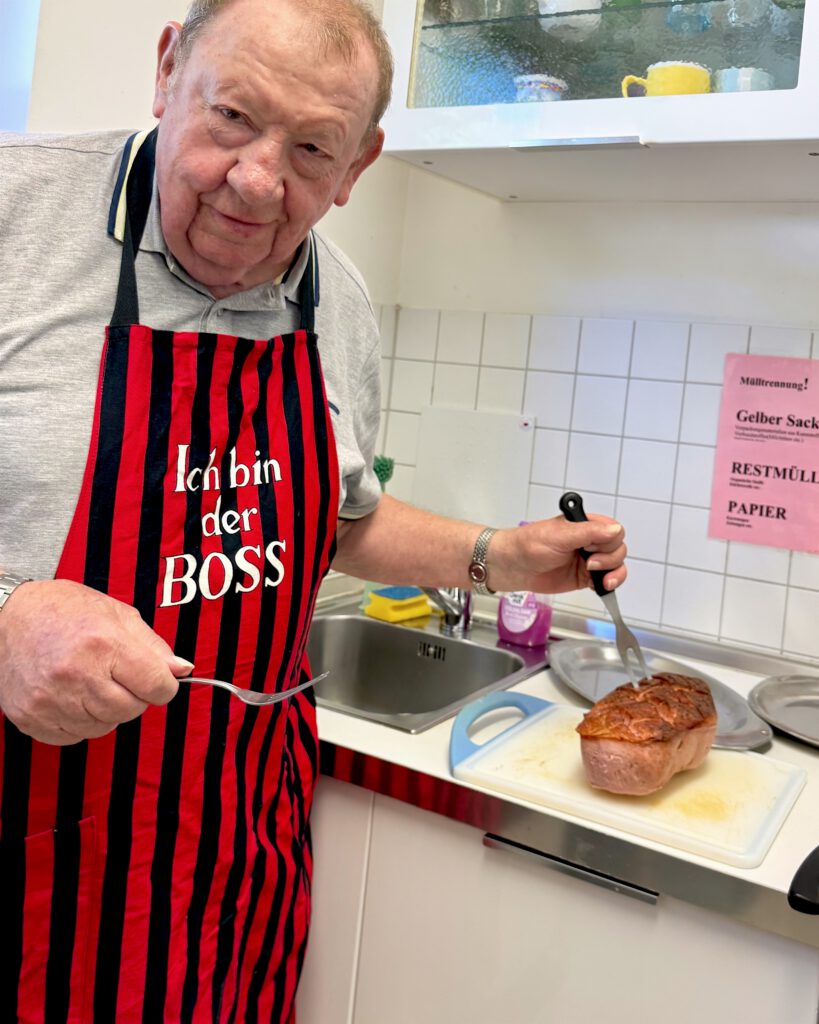Unser Gast in gestreifter Schürze beim Aufschneiden des Leberkäs.
